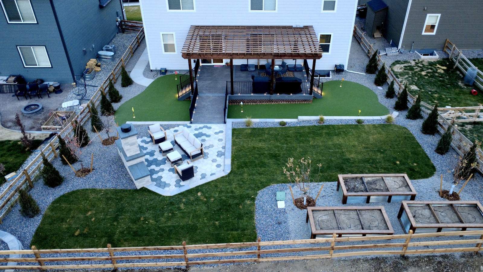 Aerial view of a full backyard transformation with pergola deck, hexagon paver patio, and putting green