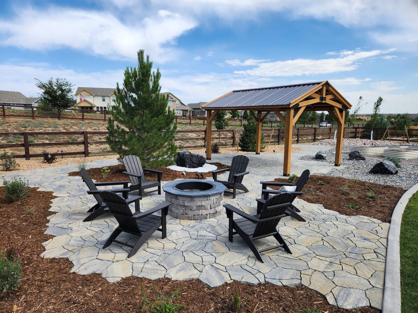 Flagstone fire pit patio with Adirondack chairs and a timber-frame cedar pavilion beyond