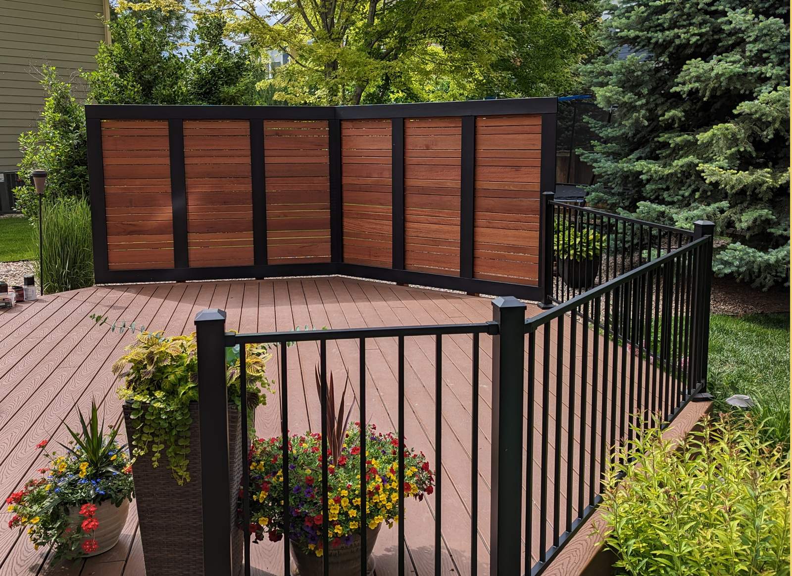 Modern composite deck with custom wood-and-black-metal privacy wall panels