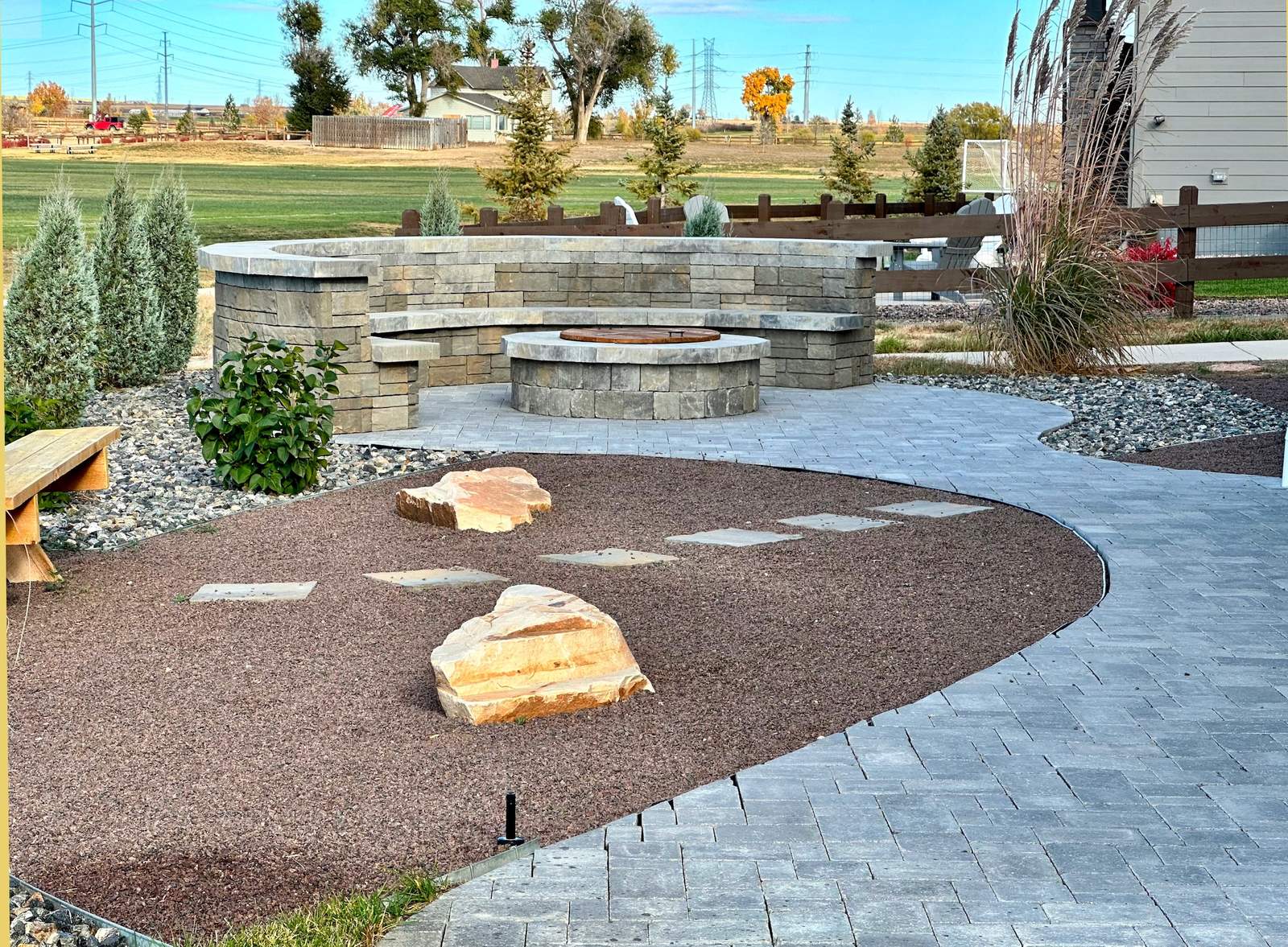 Curved natural stone seat wall with built-in fire pit and paver patio