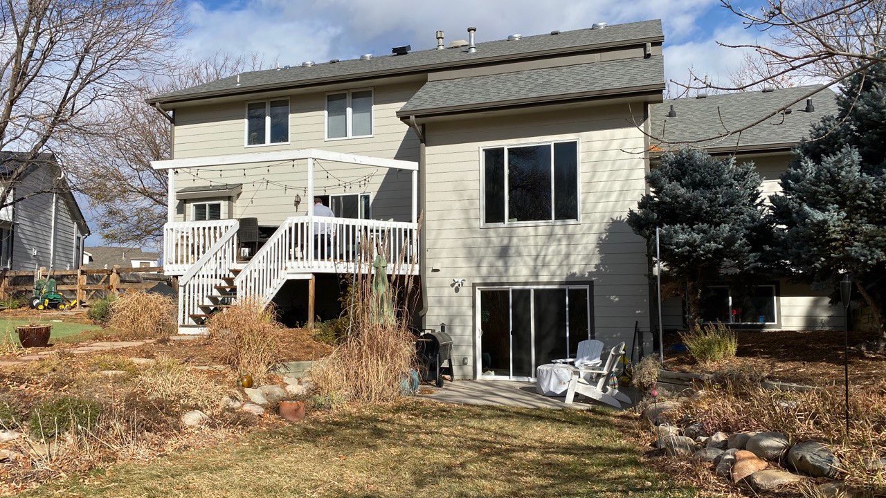Before: the same Windsor backyard with a plain white deck, dormant lawn, and overgrown beds